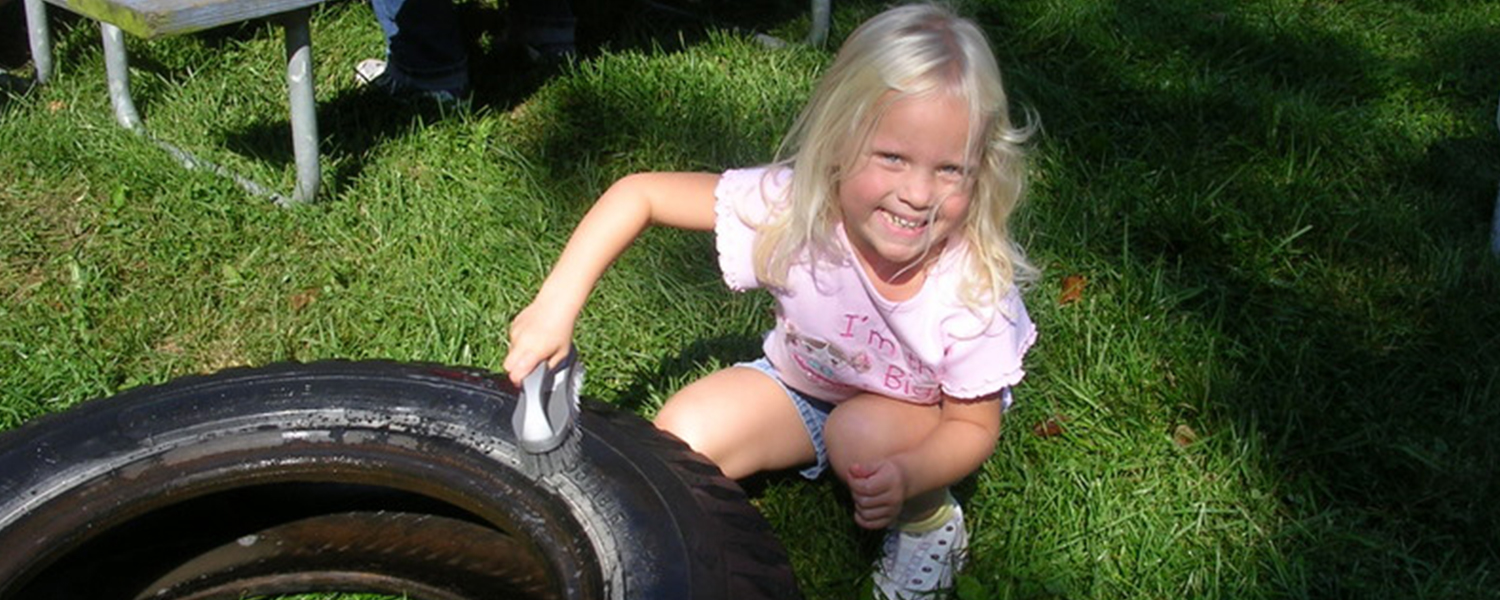 Child volunteer washes a tire for the playground